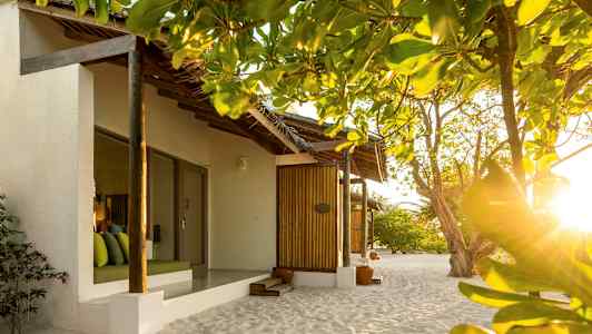 Bungalower på stranden omgitt av grøntområder og opplyst av sollys. (AI-generert tekst)