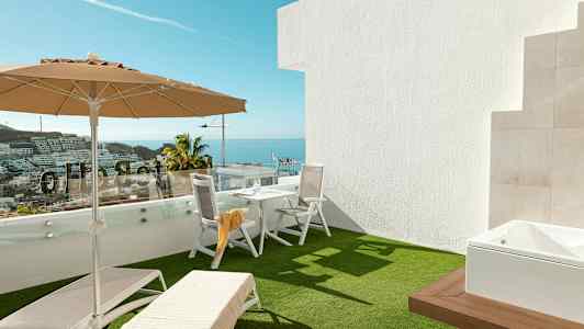 Terrasse med solsenger, parasoll og bord med stoler, havutsikt i bakgrunnen. (AI-generert tekst)