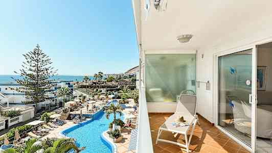 Balkong med solseng og utsikt over bassengområdet og havet. (AI-generert tekst)