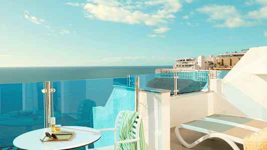 En terrasse med utsikt over havet og bygninger i bakgrunnen. (AI-generert tekst)