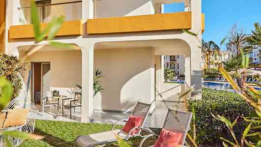 Uteplass med plen, solsenger og parasoll ved et hotell. (AI-generert tekst)