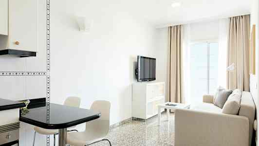 Et lyst stue med en sofa, bord, TV og spiseplass. (AI-generert tekst)