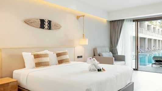 Hotellrom med seng, lenestol og utsikt over basseng fra en glassdør. (AI-generert tekst)