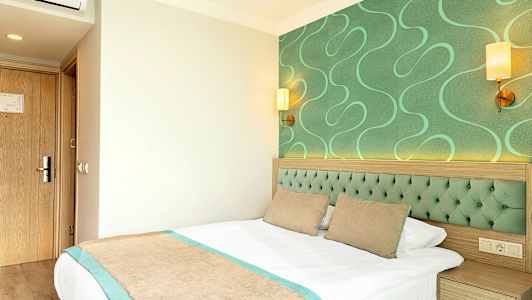 Hotellrom med grønne detaljer og en seng. (AI-generert tekst)