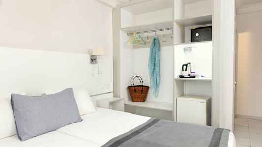 Hotellrom med seng, garderob og en minikjøleskap. (AI-generert tekst)