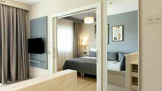 Bilde av et hotellrom med seng, speil og TV. (AI-generert tekst)