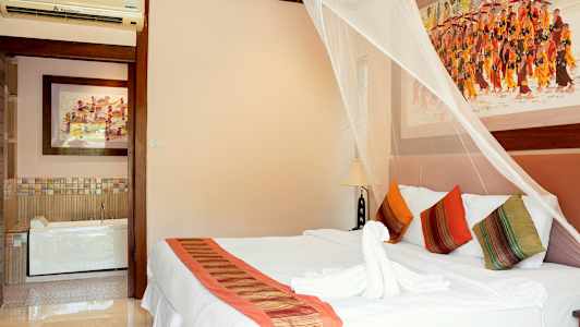 Soverom med dekorativt myggnett over en dobbeltseng, fargerike puter og kunst på veggene. (AI-generert tekst)