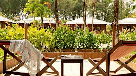 To solstoler og et bord på en terrasse med utsikt over en hage. (AI-generert tekst)