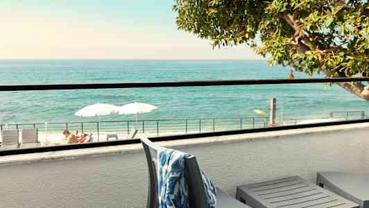 Terrasse med utsikt over havet, solsenger og parasoller synlige. (AI-generert tekst)