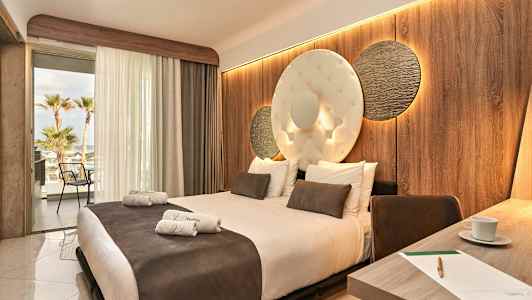 Hotellrom med en stor seng, dekorert vegg og åpen balkong med utsikt. (AI-generert tekst)