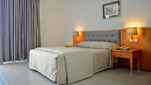 Hotellrom med en seng og to sengelamper. (AI-generert tekst)