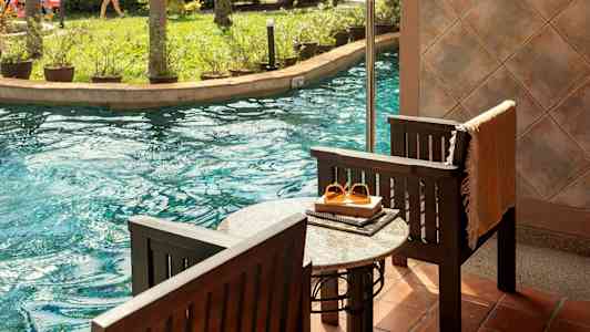 Terrasse ved bassenget med utsikt mot en hage og vannsklie. (AI-generert tekst)