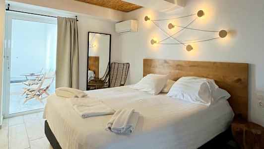 Bilde av et hotellrom med en dobbeltseng, treinnredning og moderne lysarmaturer på veggen. (AI-generert tekst)