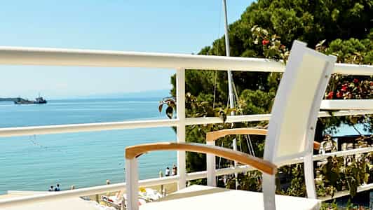 En hvit stol står på en balkong med utsikt over havet. (AI-generert tekst)