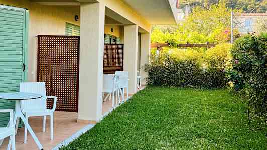 Utvendig bilde av en bygning med plen og sitteplasser utenfor. (AI-generert tekst)