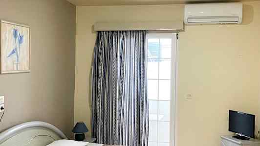 Hotellrom med to enkeltsenger, en TV og et vindu med gardiner. (AI-generert tekst)