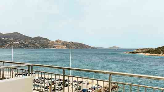 Utsikt fra en balkong mot havet med fjell i bakgrunnen. (AI-generert tekst)