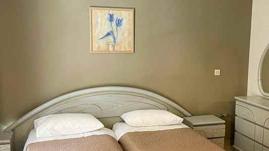 To enkeltsenger med brune sengetepper, et maleri på veggen over og en kommode til høyre. (AI-generert tekst)