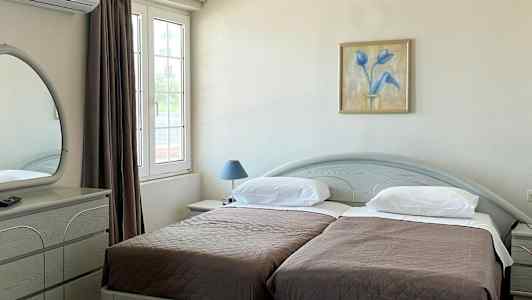 Hotellrom med to enkeltsenger, et skrivebord og et speil. (AI-generert tekst)