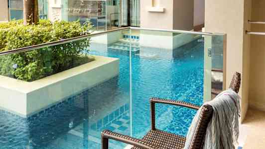 En balkong med utsikt over et basseng og nærliggende bygninger. (AI-generert tekst)