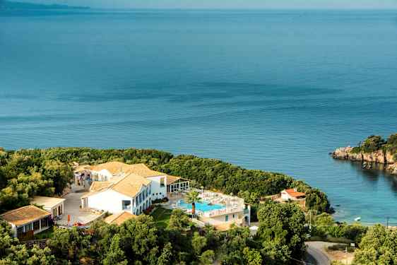 Hotellbygning med basseng og omkringliggende grønne områder ved sjøen. (AI-generert tekst)