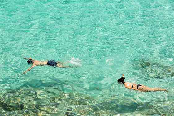 To personer snorkler i klart turkis vann. (AI-generert tekst)