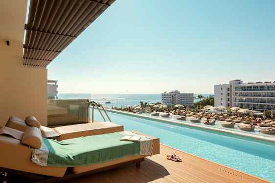 Solstoler og basseng med utsikt over havet på en ferieby. (AI-generert tekst)