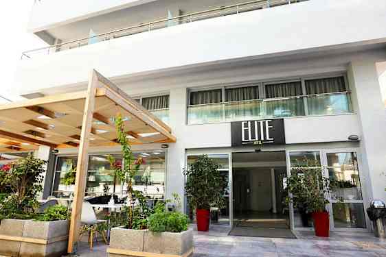 Hotellinngang med skilt som viser 'Elite Hotel', omgitt av planter og blomster. (AI-generert tekst)