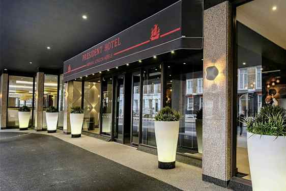 Inngangen til President Hotel med store hvite krukker fylt med grønt. (AI-generert tekst)