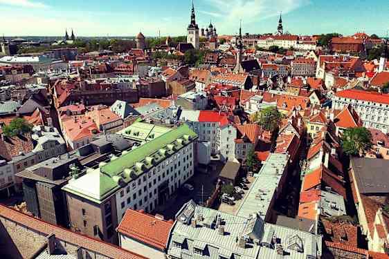 Flyfoto av en by med eldre bygninger i forskjellige farger. (AI-generert tekst)