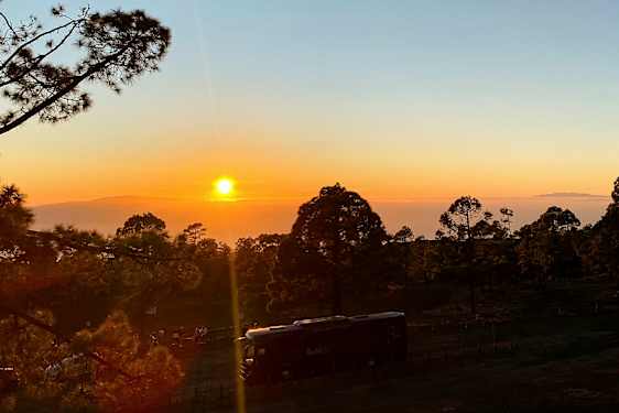 Bilde av en solnedgang over en skog med et kjøretøy i forgrunnen. (AI-generert tekst)