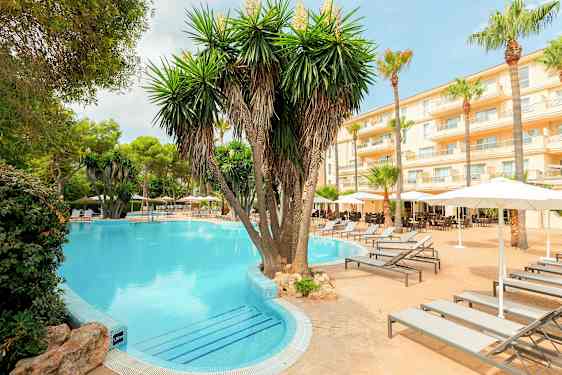 Hotellområde med basseng, palmer og solsenger. (AI-generert tekst)