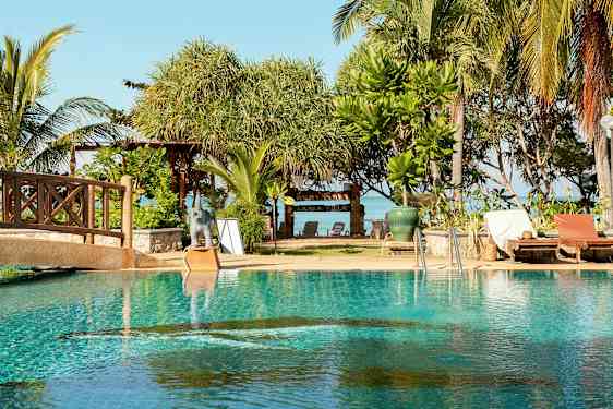 Et basseng med solsenger ved siden av, og bak er det trær og et skilt med teksten 'Lanta Villa'. (AI-generert tekst)