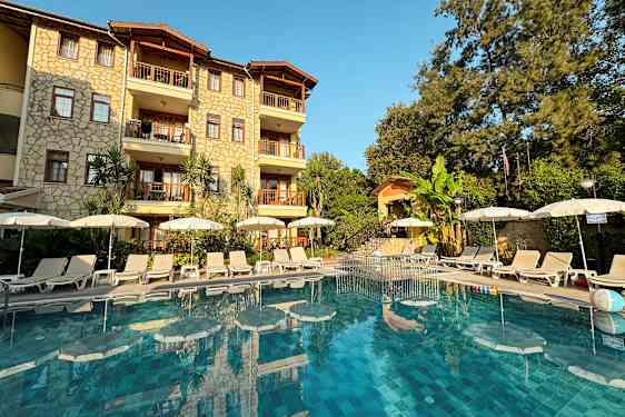 Bilde av hotellfasade med basseng og solsenger foran. (AI-generert tekst)