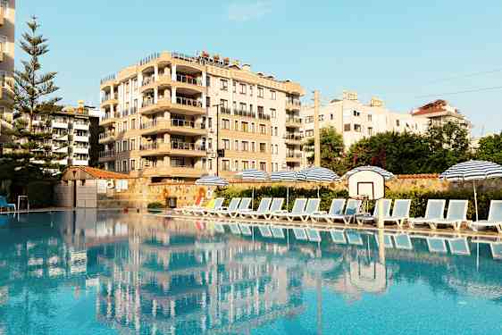 Bilde av et basseng med solsenger og parasoller på siden, samt en bygning i bakgrunnen. (AI-generert tekst)