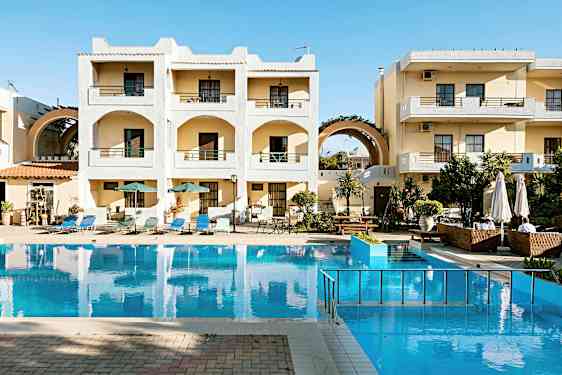 Et hotellkompleks med balkonger og et basseng foran bygningen. Det er solsenger og parasoller rundt bassenget. (AI-generert tekst)