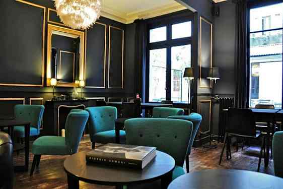 Et elegant innredet rom med sittegrupper og blå lenestoler samt store vinduer. (AI-generert tekst)