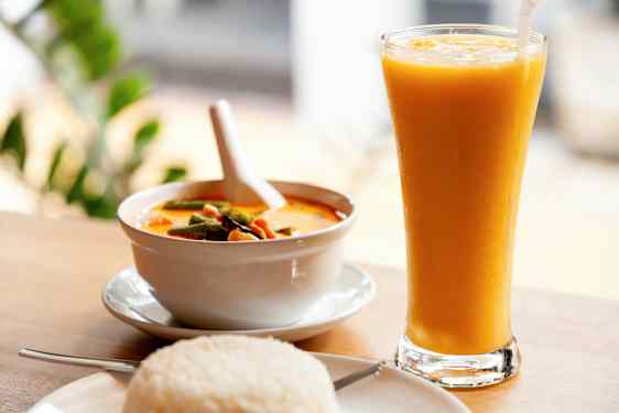 En bolle med gul karri, en tallerken med ris og et glass med gul drikke. (AI-generert tekst)