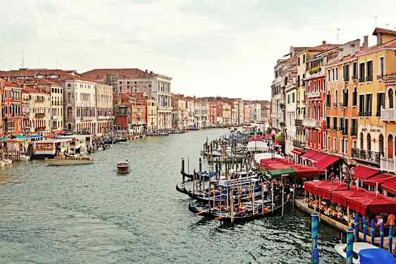 En kanal med gondoler og fargerike bygninger på begge sider i Venezia. (AI-generert tekst)