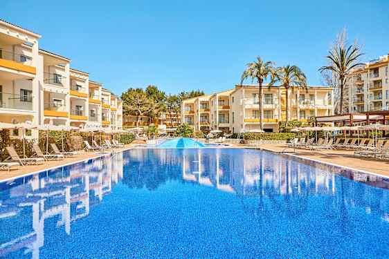 Bilde av et utendørsbasseng med bygninger og solsenger i bakgrunnen. (AI-generert tekst)