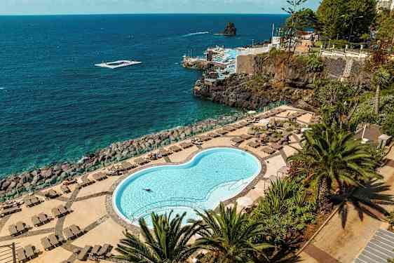 Lukket basseng med solsenger og utsikt over havet. (AI-generert tekst)