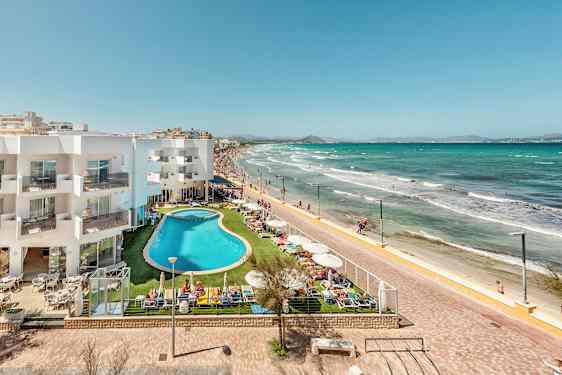 Hotellbygning og bassengområde ved strandpromenade og sandstrand. (AI-generert tekst)