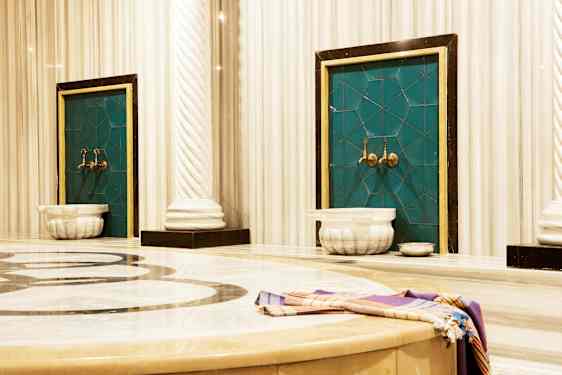 Bilde av et tradisjonelt hamam med marmoroverflater og vannkraner. (AI-generert tekst)