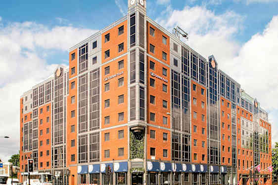 Bilde av et hotell med røde murstein og glassvinduer. (AI-generert tekst)