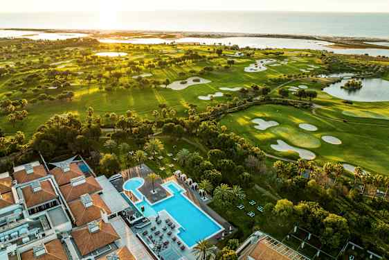 Luftfoto av golfbaner og et hotell med bassengområde. (AI-generert tekst)