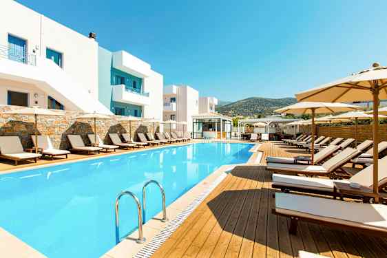 Utendørs svømmebasseng og solsenger ved hotellbygning. (AI-generert tekst)