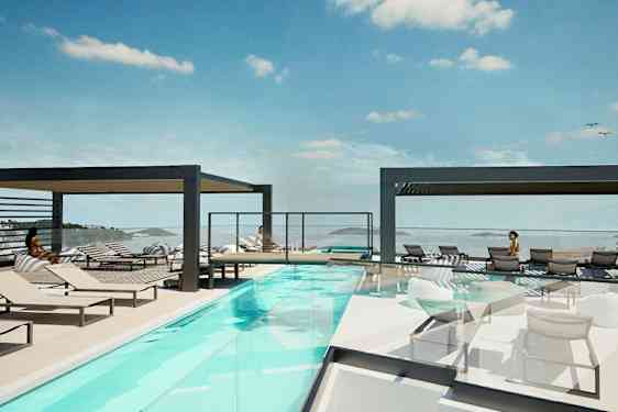 Et utendørsbasseng med solsenger og utsikt over havet. (AI-generert tekst)