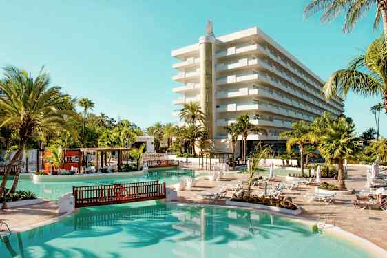 Hotell med bassengområde, solsenger og palmer. (AI-generert tekst)