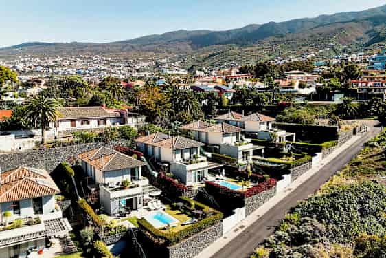 Bilde av et område med moderne hus og små bassenger omgitt av grøntområder og en vei. (AI-generert tekst)