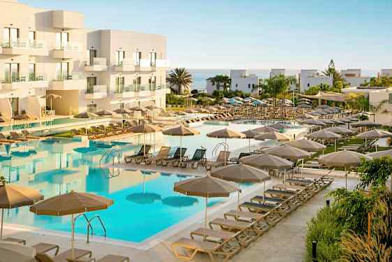 Bilde av et hotellbasseng med solsenger og parasoller i et ferieområde. (AI-generert tekst)
